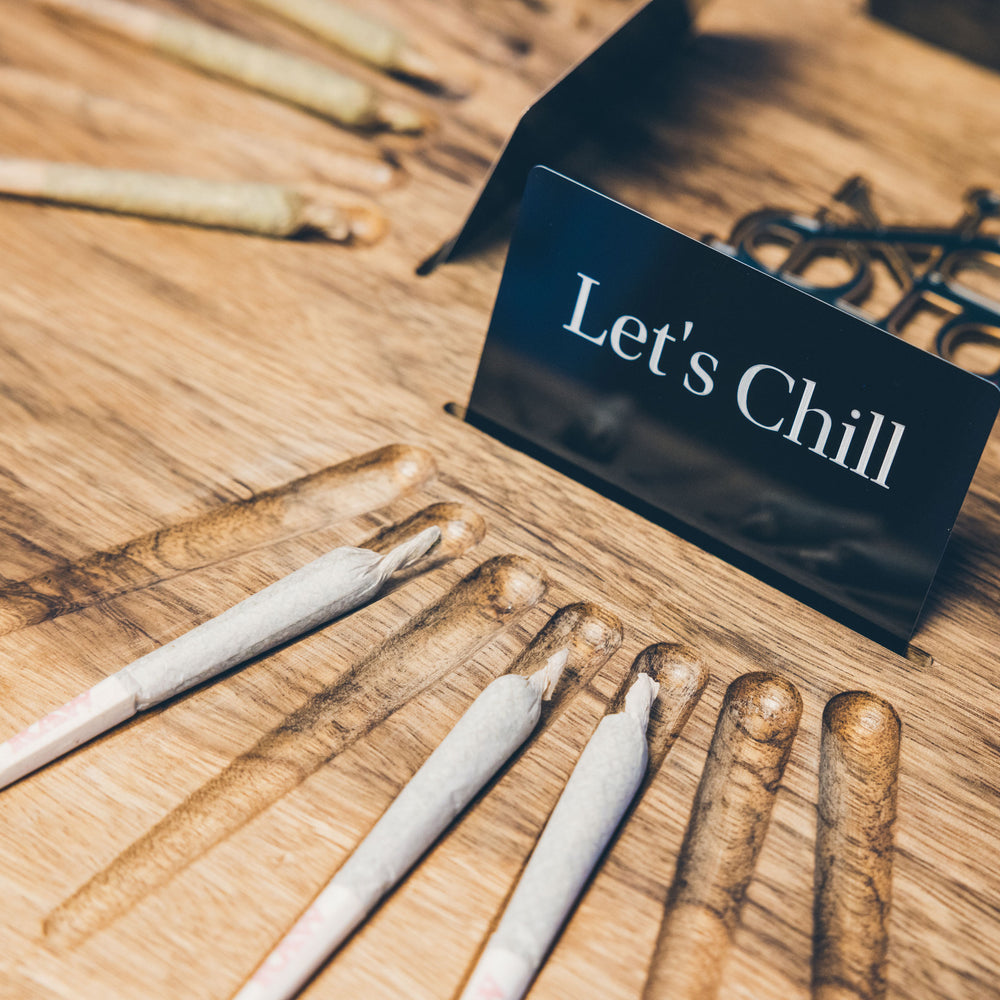 A stylish tabletop display featuring pre-rolled joints and a sign reading 'Let's Chill' on a wooden surface.